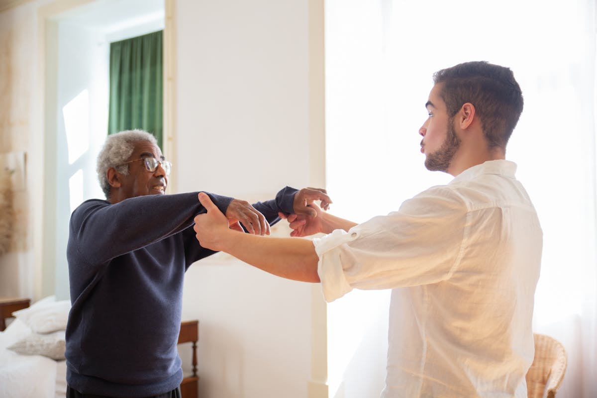 An older man in conversation with a supportive caregiver, representing unpaid care in the UK