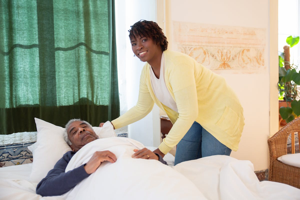 A carer sitting with an older adult at home, offering comfort and support