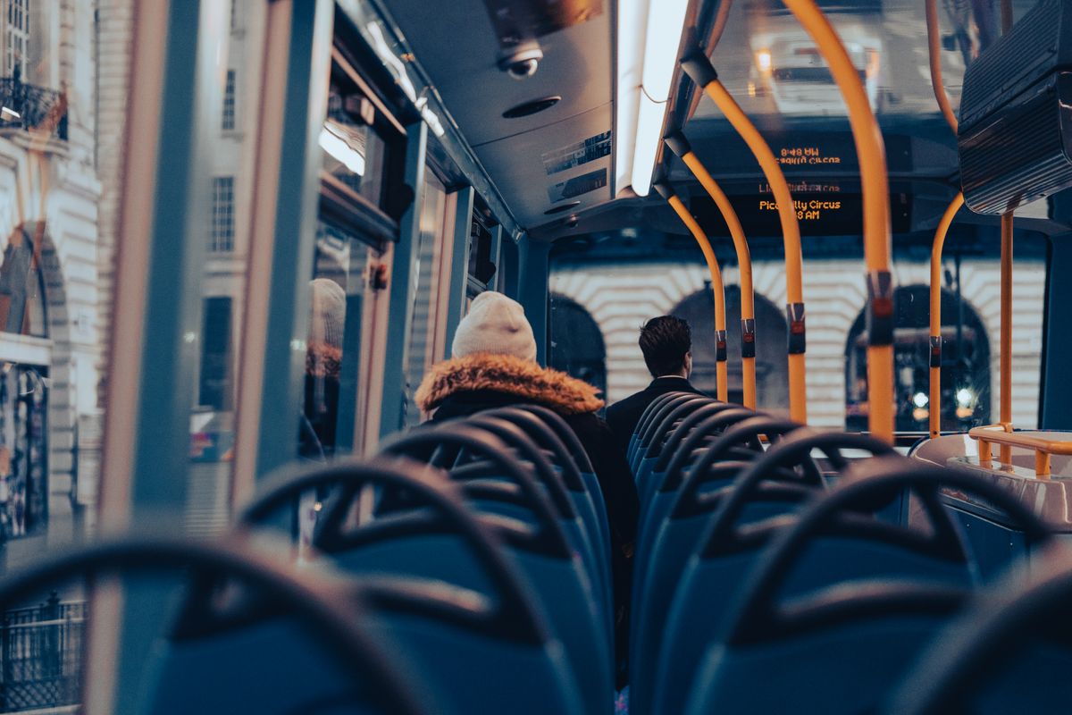 Two older adults sitting on a bus, smiling during a day trip