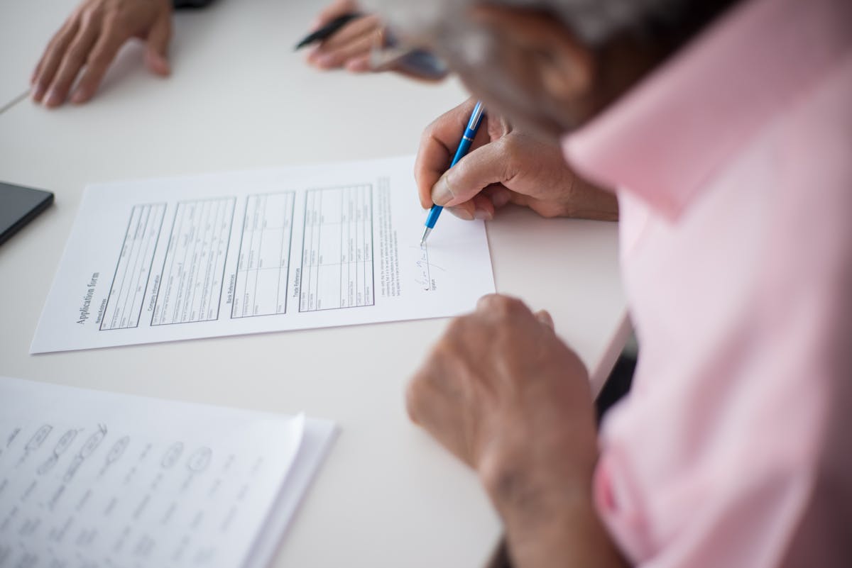 An older man signing a legal document at a desk