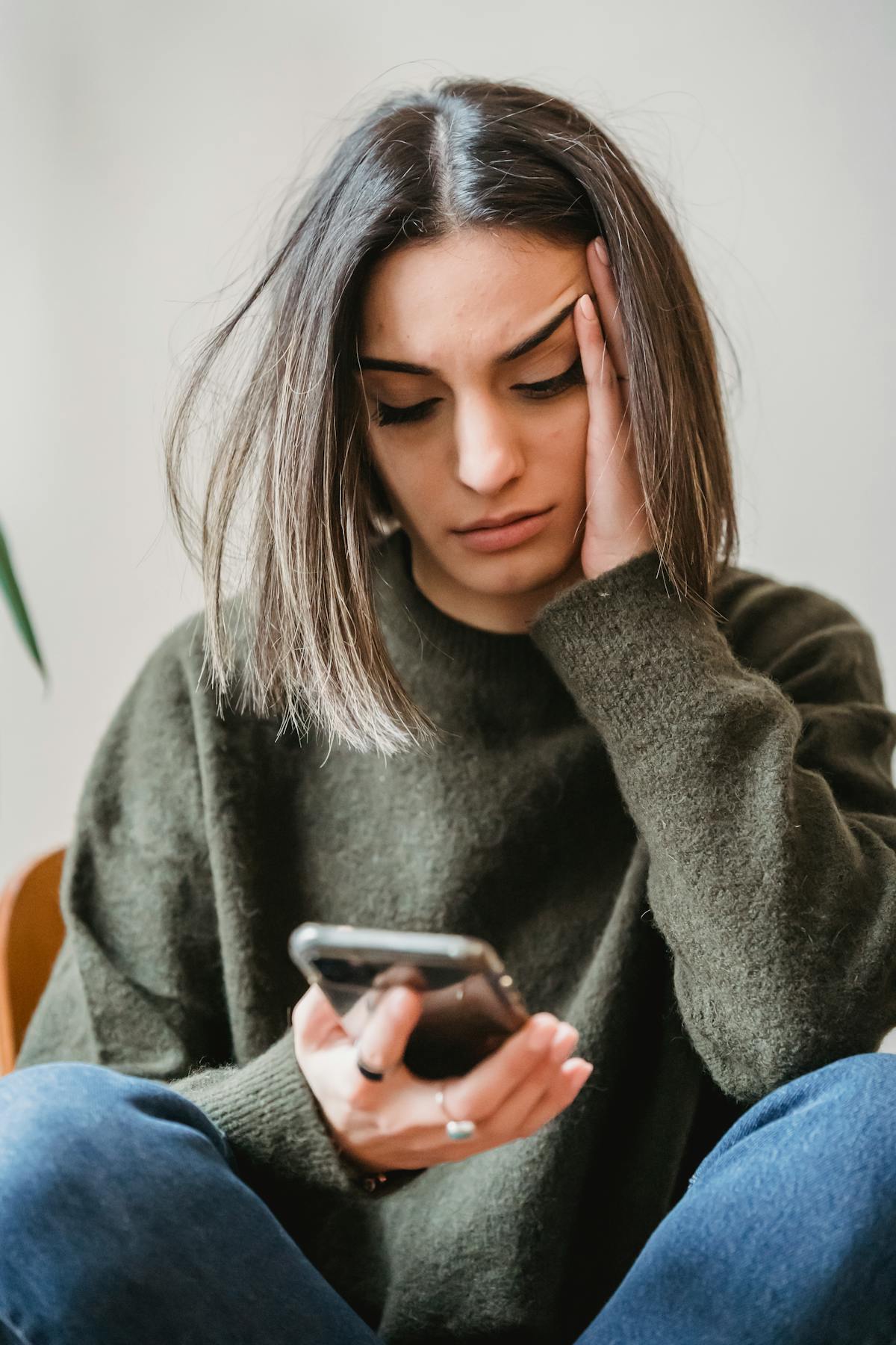 A woman looking concerned while reading a message on her smartphone
