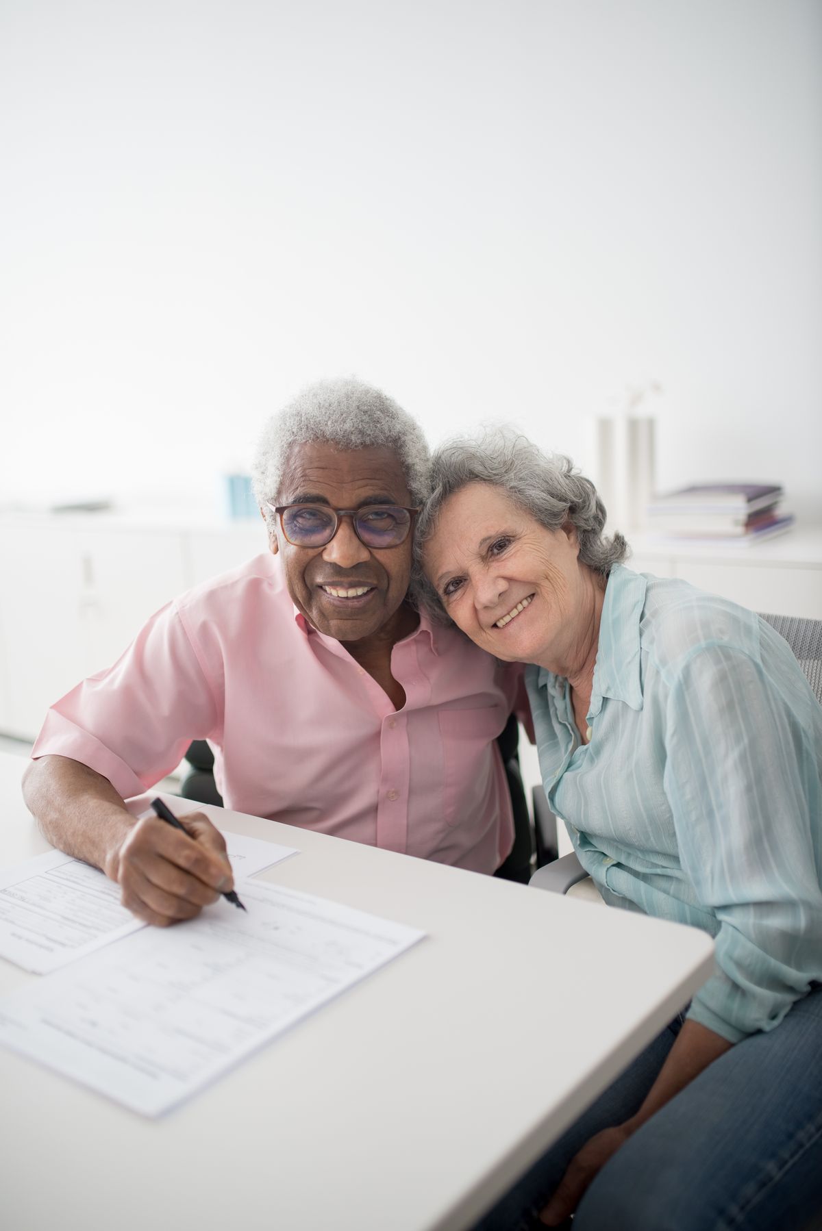 An older couple sitting at a table signing legal documents together